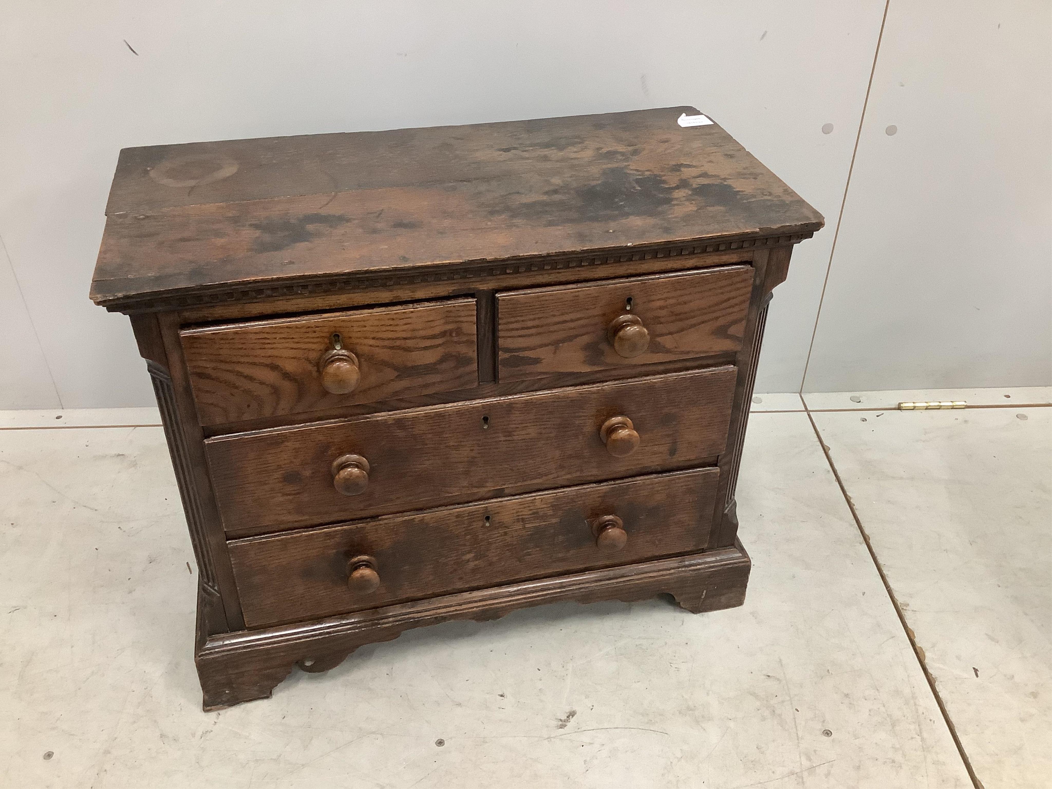 An 18th century miniature oak chest of two short and two long drawers, possibly child’s furniture, width 67cm, depth 34cm, height 55cm. Condition - fair, top timber join separated, one scroll detail missing from right br